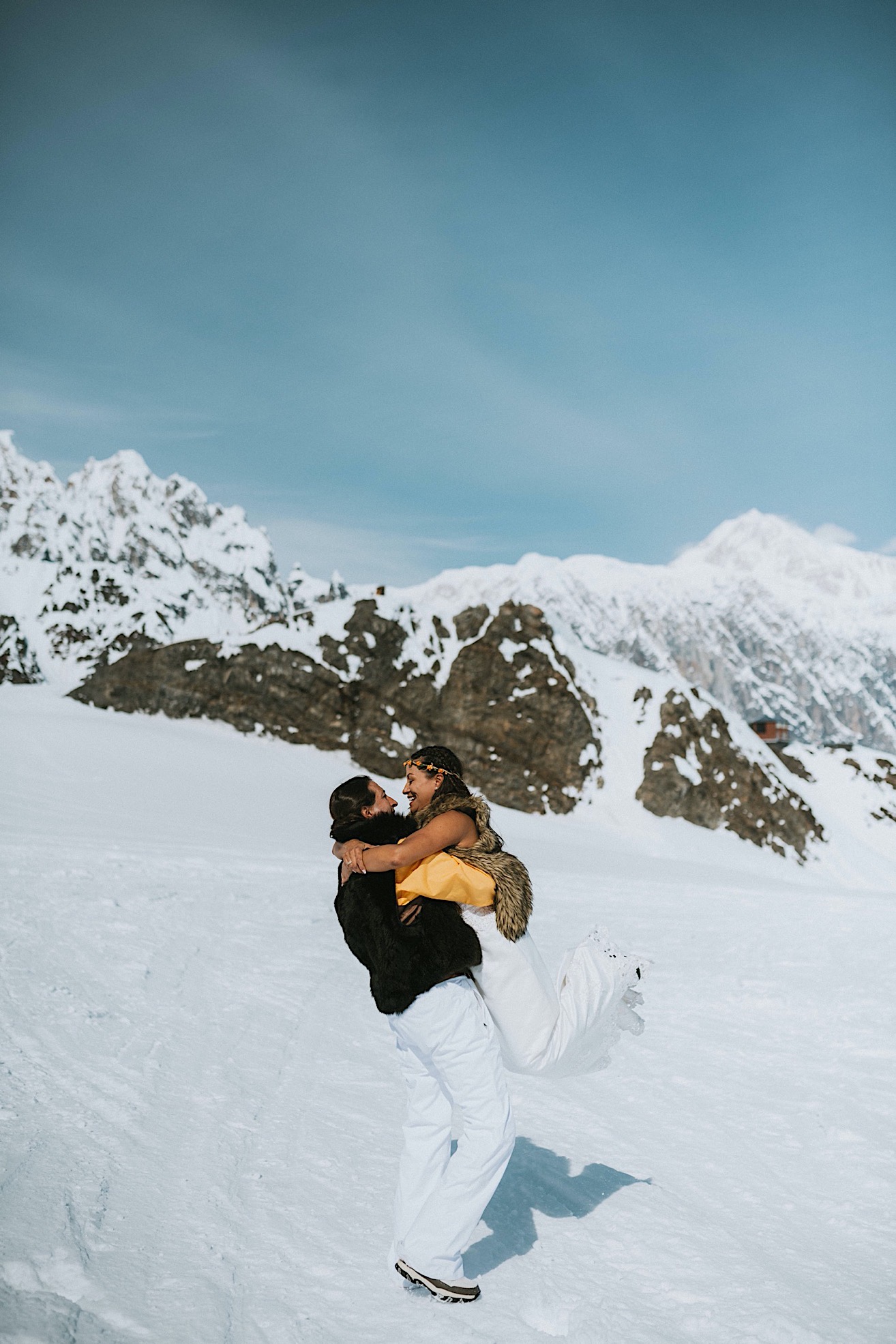 Groom picking up his bride and spinning her around after their glacier elopement
