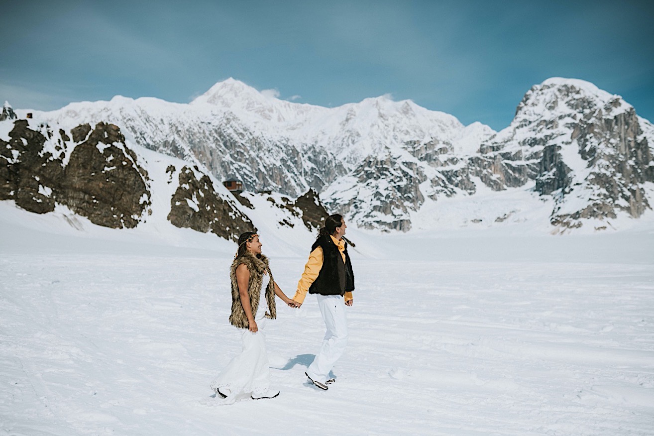 Groom leading his bride across snow on ruth glacier