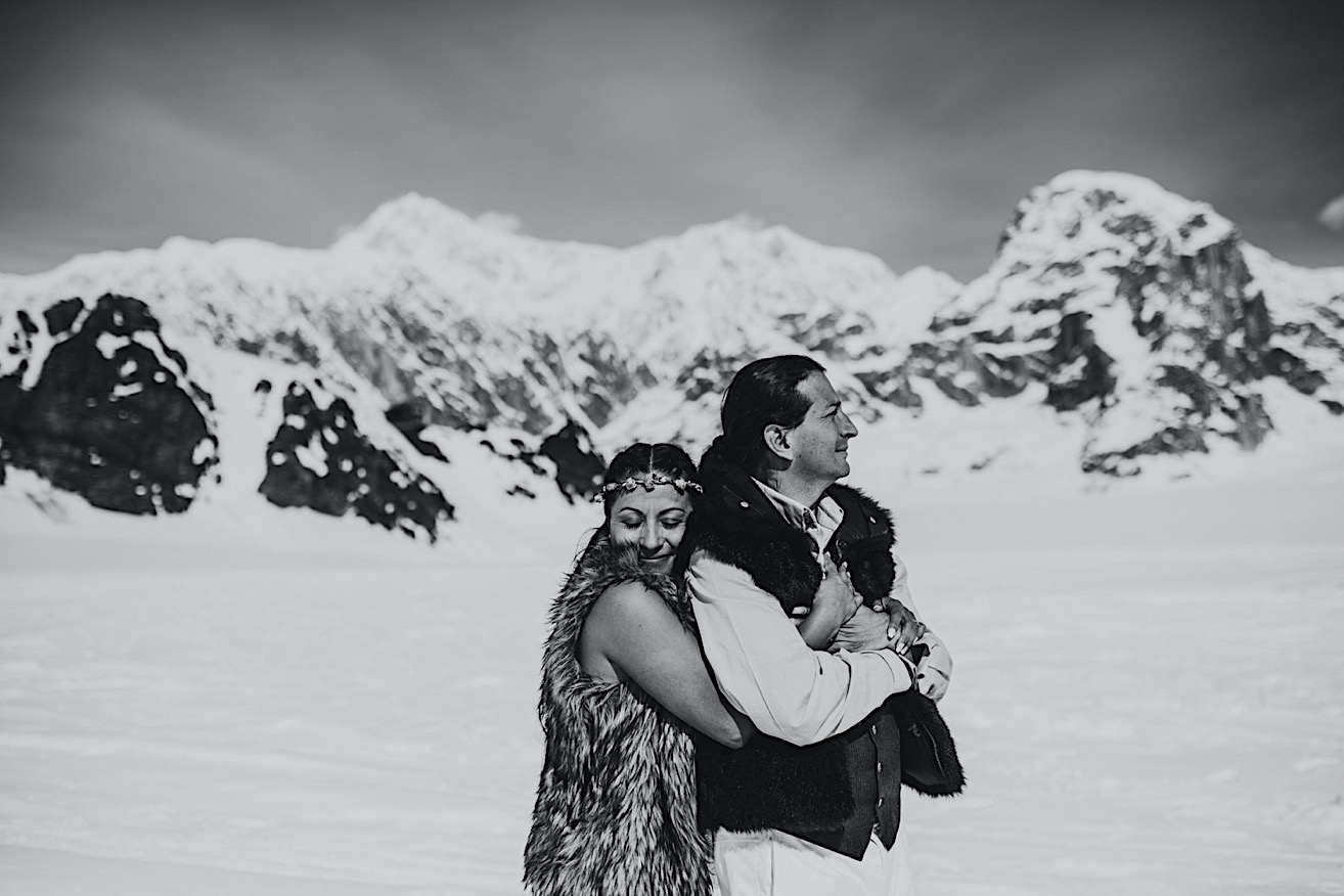 Black and white photo of Bride bear hugging her groom in front of the mountains in Denali 