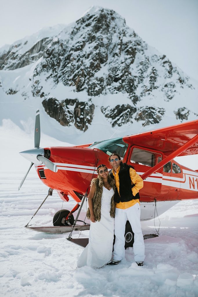 Photo of the couple smiling in front of the red airplane from sheldon air services
