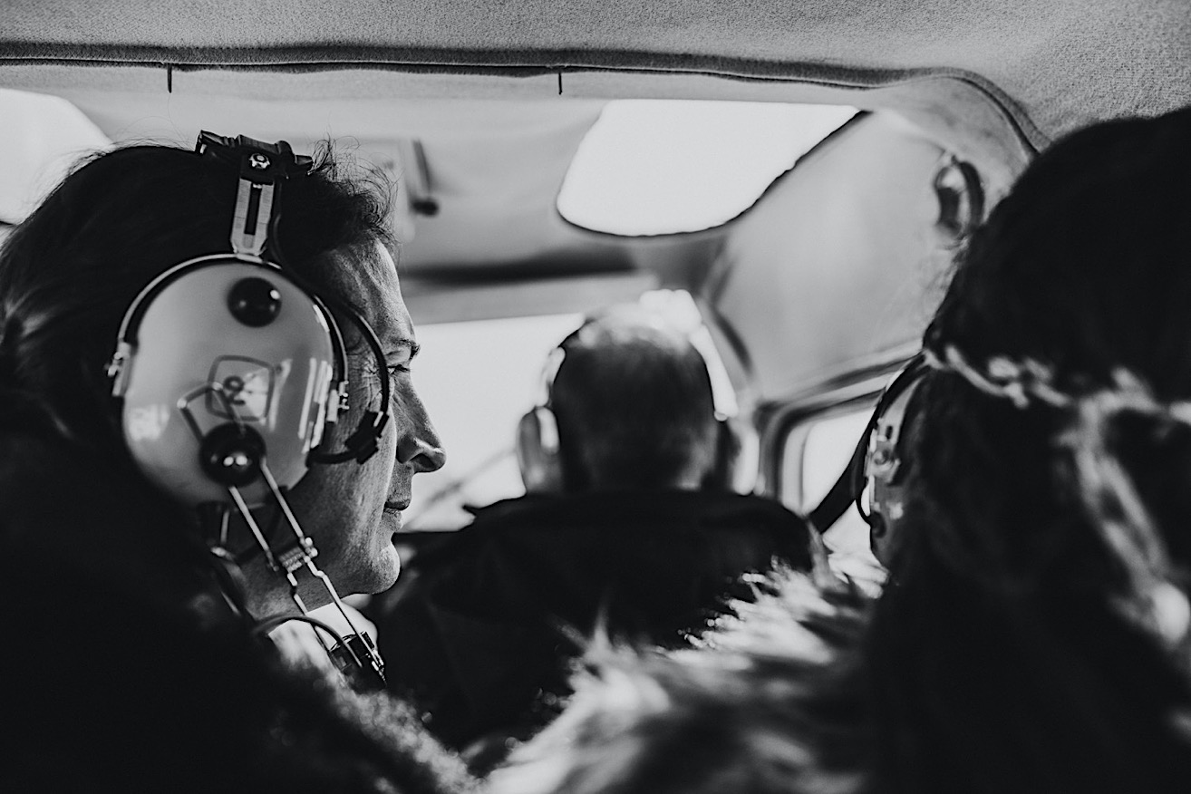 Black and white photo of groom inside of a plane looking out the winter