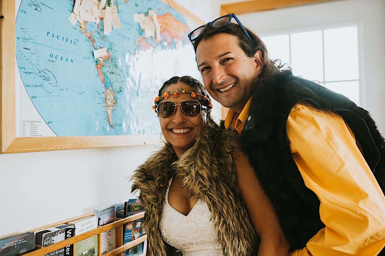 Bride and groom smiling in front of the map of the world with their pin on Colombia