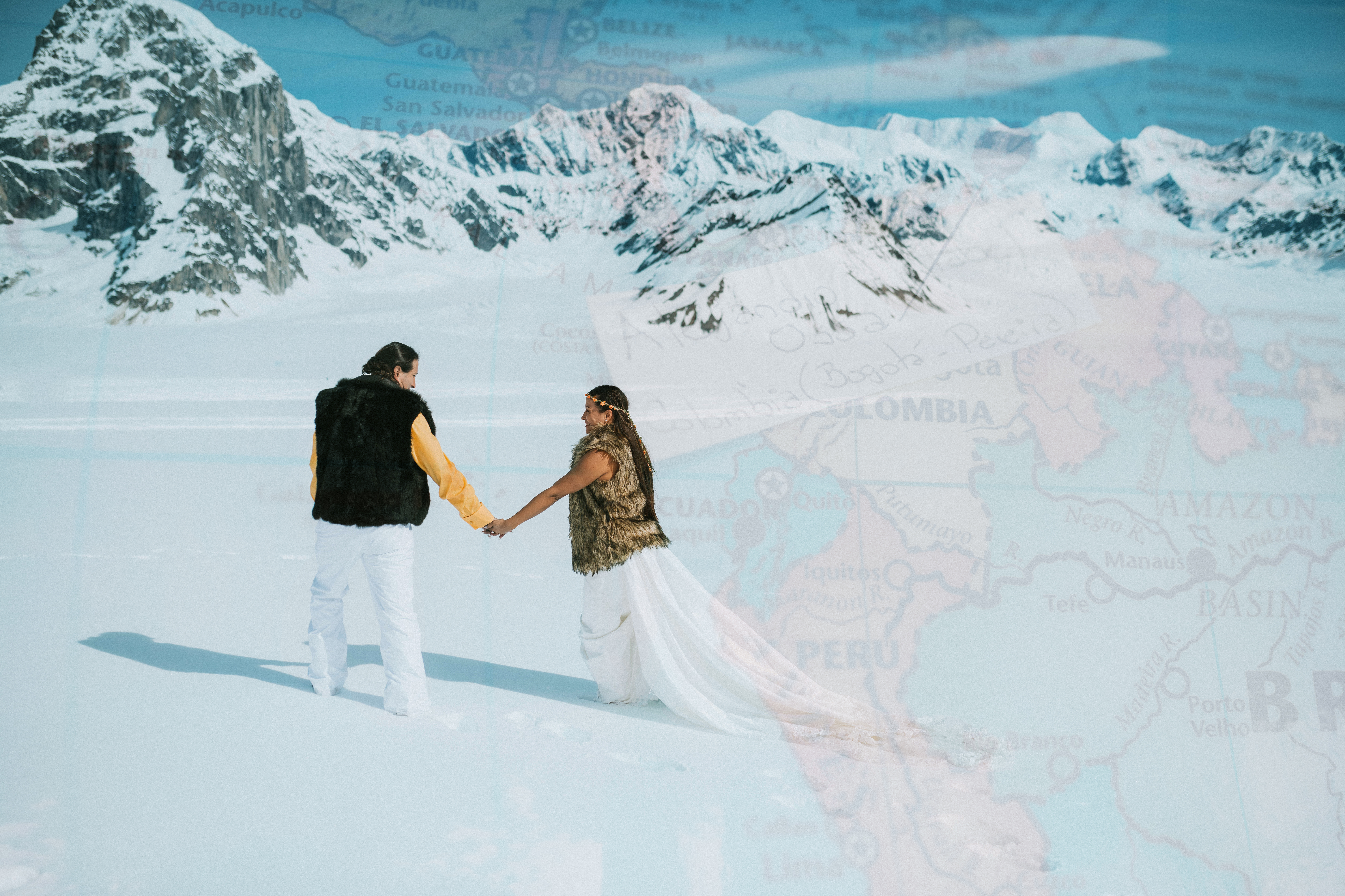 Bride and groom holding hands as groom leads the way across the pristine snow on the glacier, the image is overlaid by a map of Colombia with their names and a pin to mark where they are from