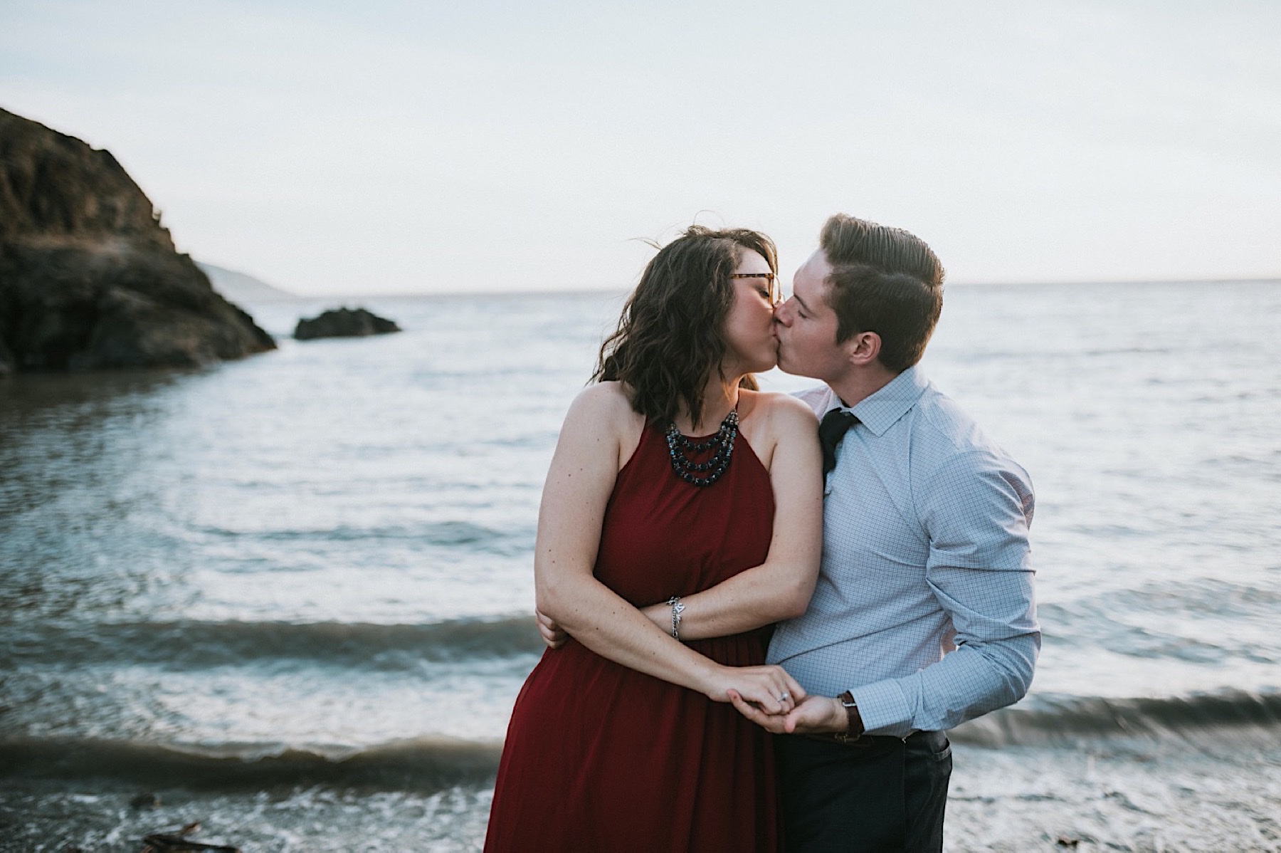 Couple wrapped up in a hug and kiss during engagement session at Beluga Point