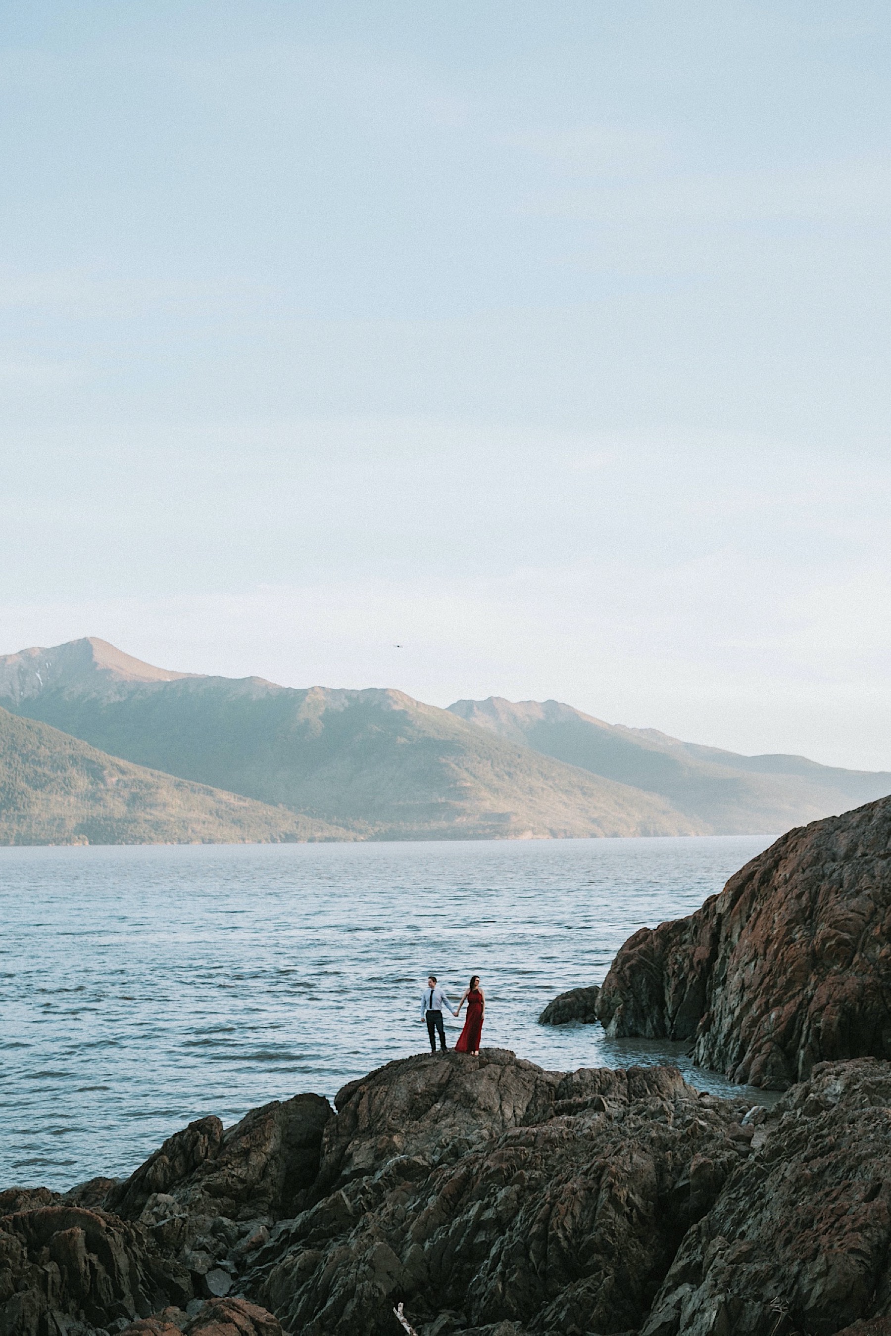 Couple standing side by side holding hands looking outwards towards the mountains at Beuga Point