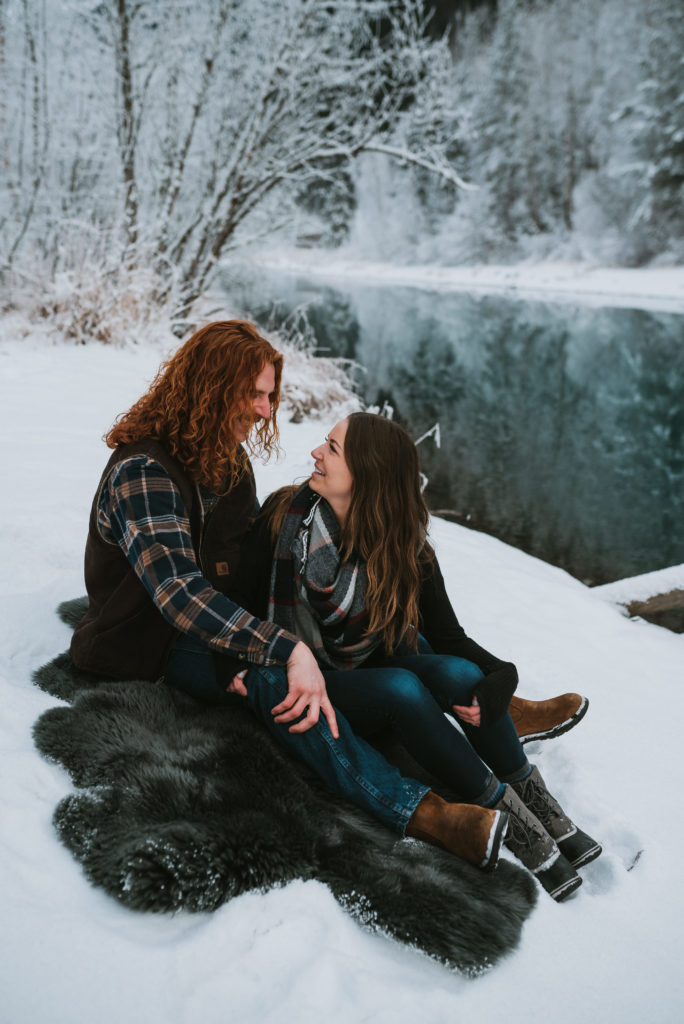 Couple sitting in the snow together at Eklutna Tailrace, Alaska