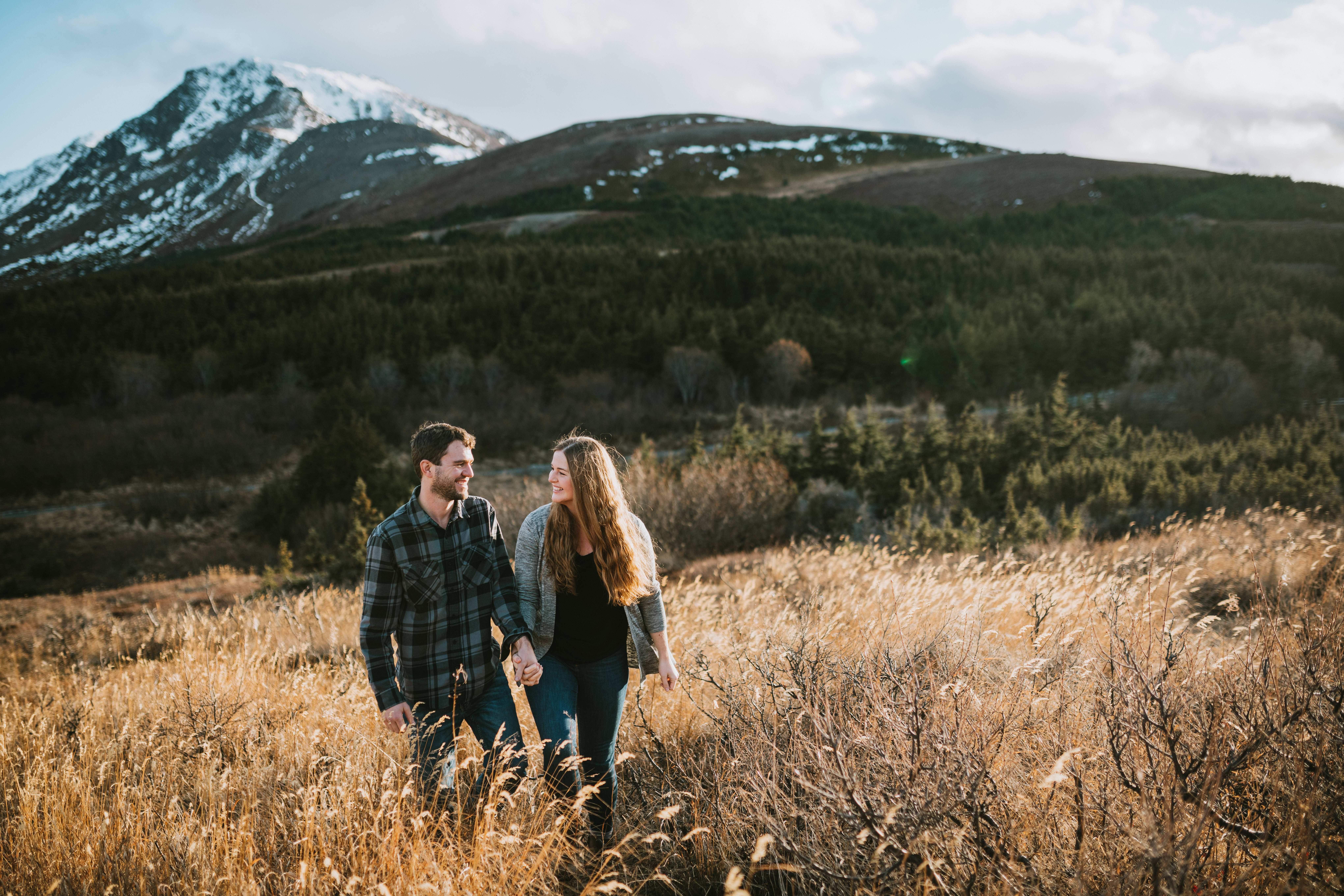 Couple walking and smiling during tall grass during their Engagement session in Alaska