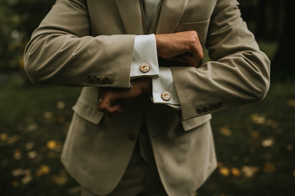 Groom showing off his custom mountain cufflinks with the wedding date and last name