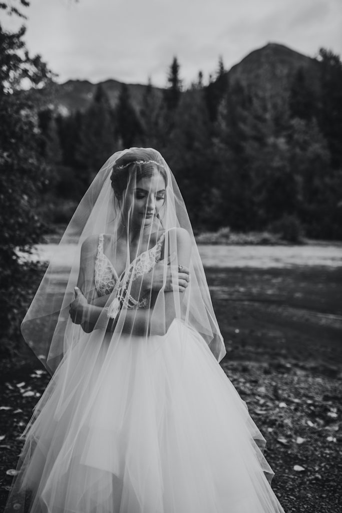 Black and white images of bride delicately hugging herself under her veil