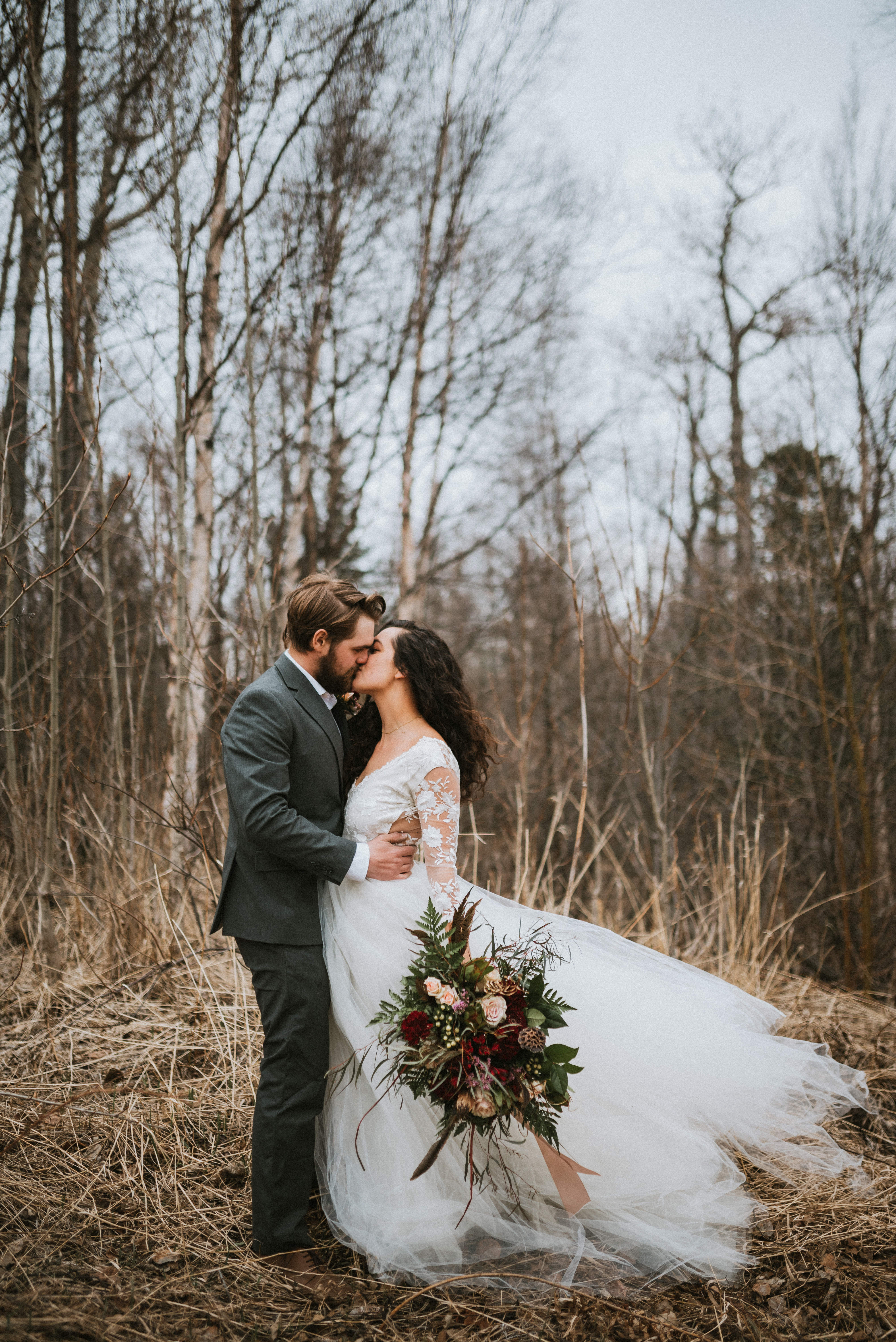 boho bride and groom kissing in tall dead grass