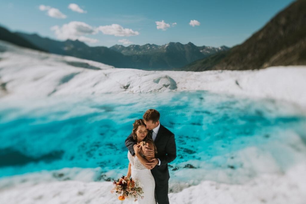 couple snuggling in front of a glacier pool on spencer glacier