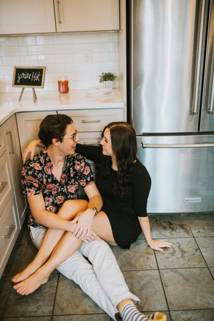 A couple snuggling in their kitchen during a date night enjoying each others company and smiling at each other