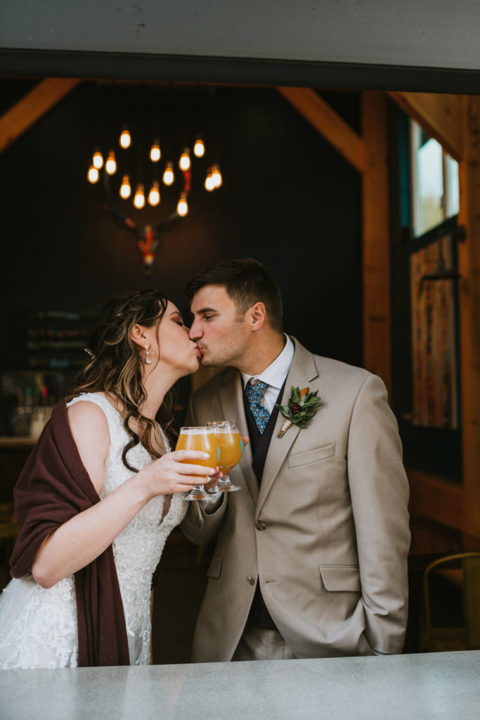 Bride and groom sharing a kiss while cheersing their beer
