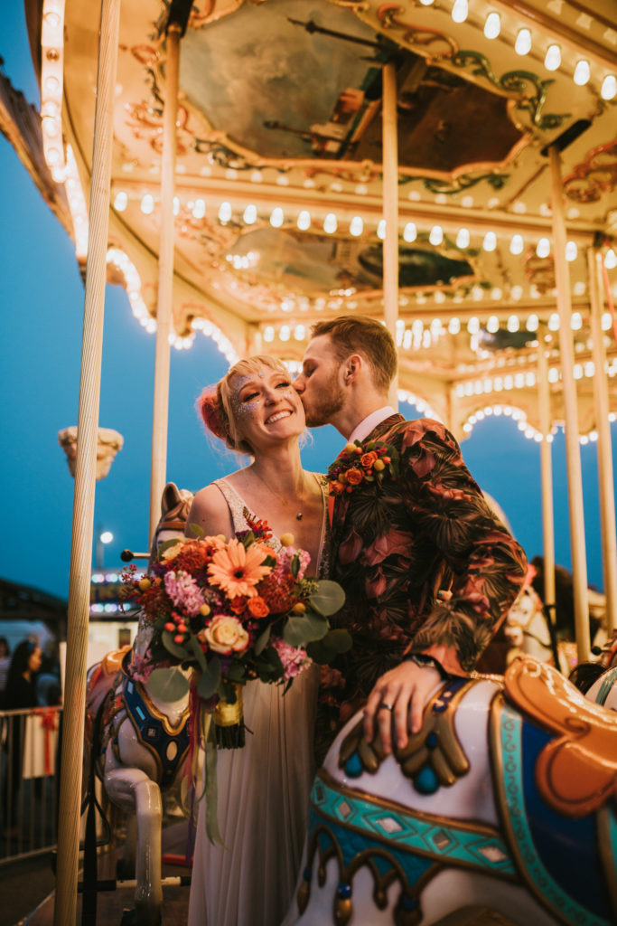 Bride and groom sitting on the merry go round snuggling at the Alaska state fair