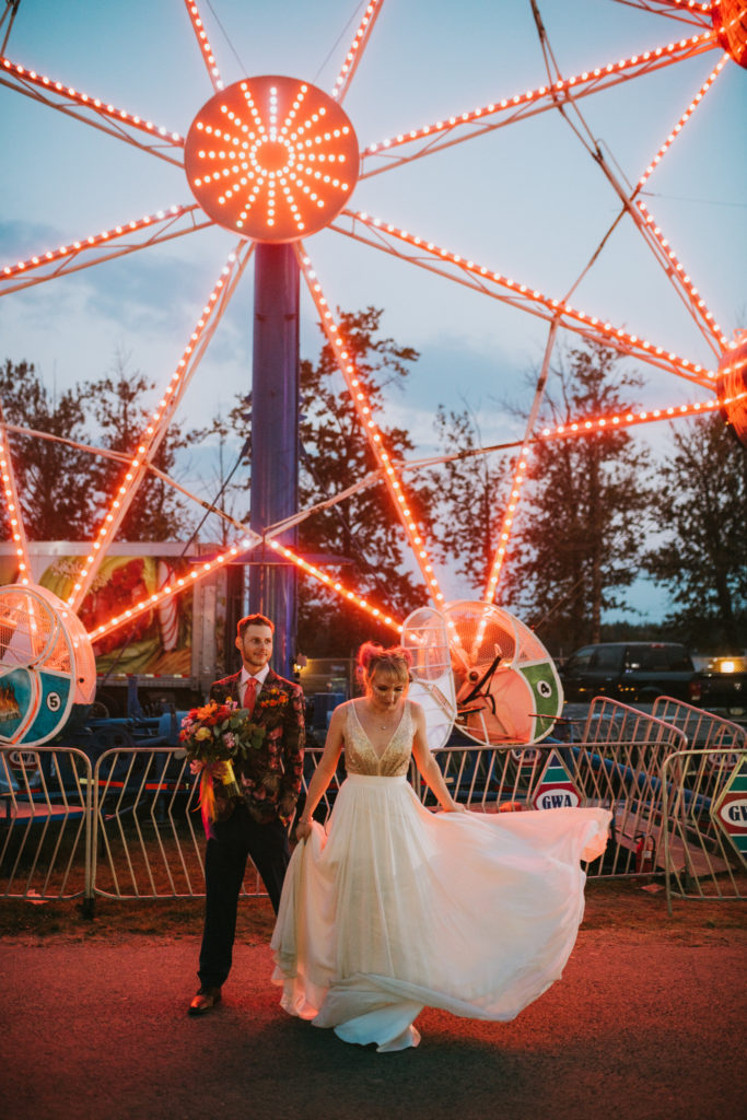 Bride and groom standing in front of red neon fair lights at the alaska state fair