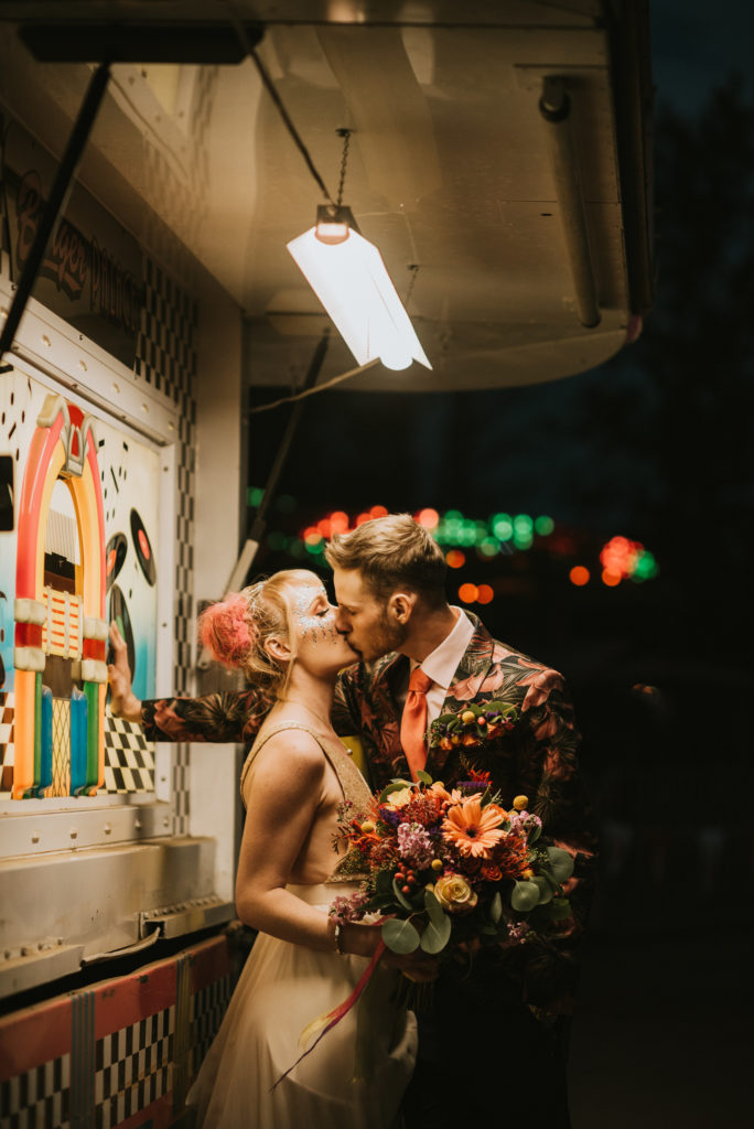 Bride and groom leaning against fair booth in fluorescent light at Alaska state fair