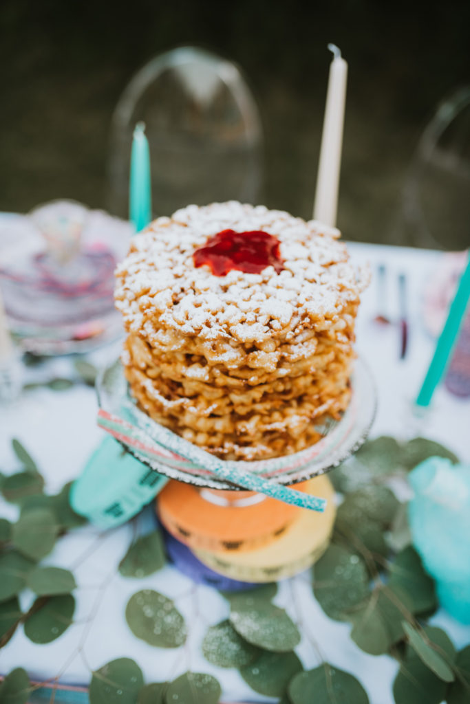 Funnel cake wedding cake sprinkled with powdered sugar and topped with jelly