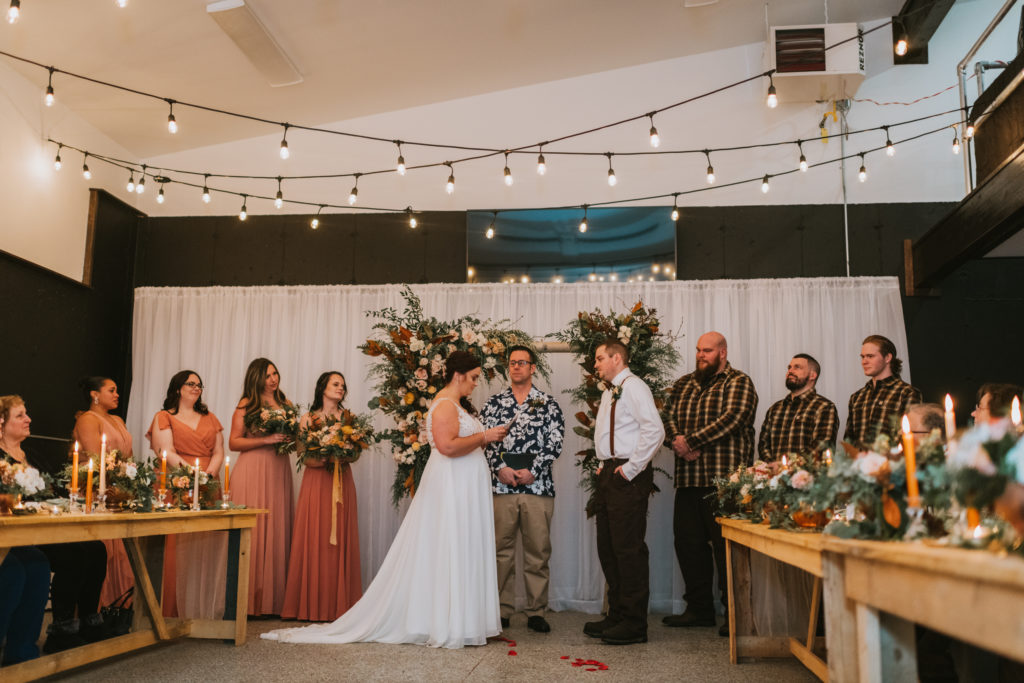 Bride reading vows during ceremony in indoor space with twinkle lights