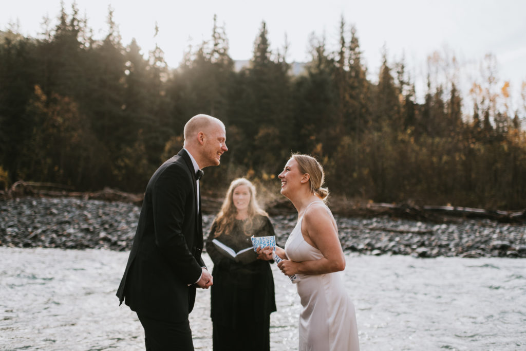 bride reading wedding vows from an old parking ticket on girdwood riverbed