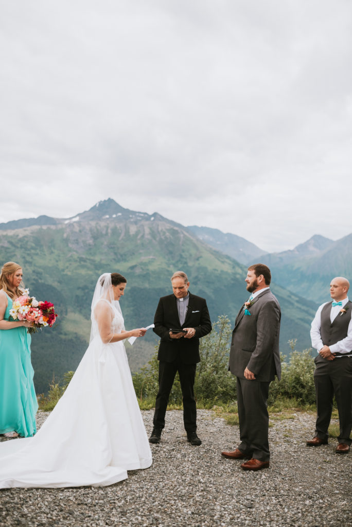 bride reading her vows during ceremony against the Alyeska backdrop