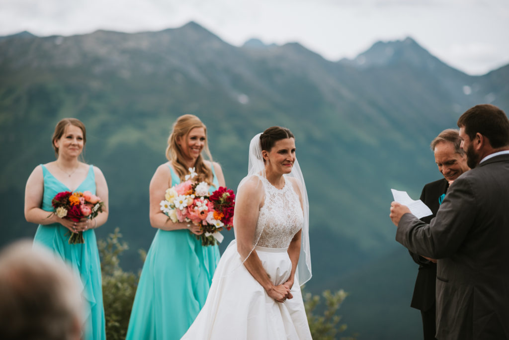 bride emotionally listening to her grooms vows against mountain backdrop