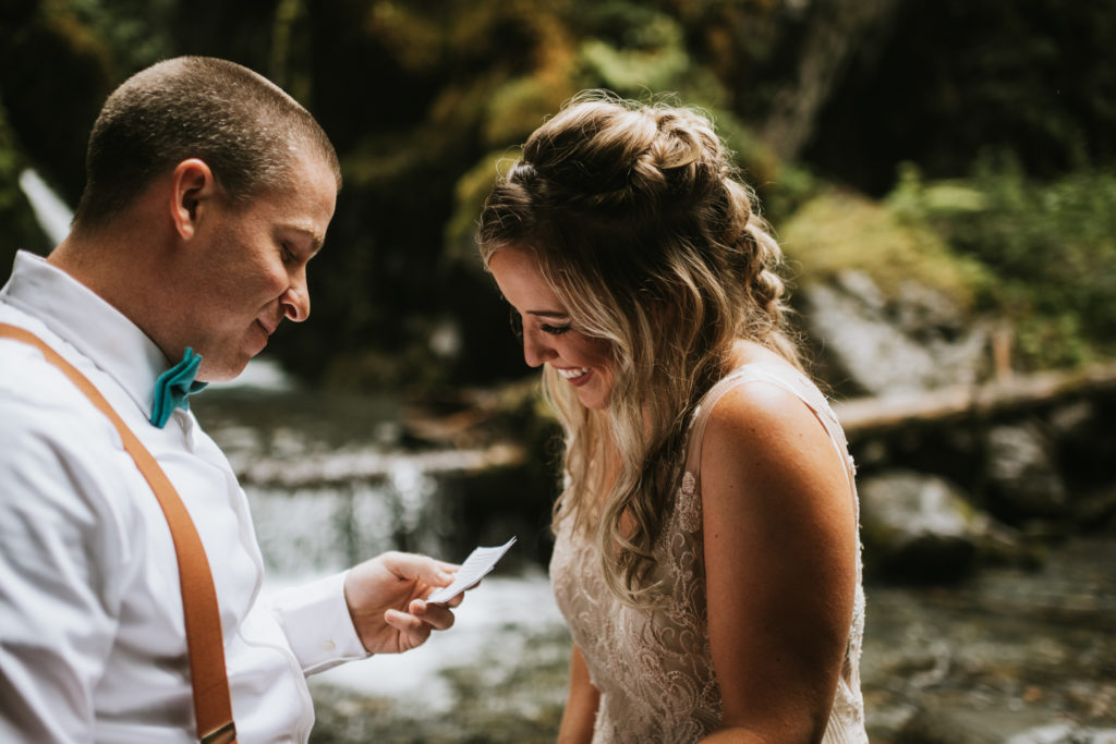 Bride laughing and smiling as she listens to her husband read his vows