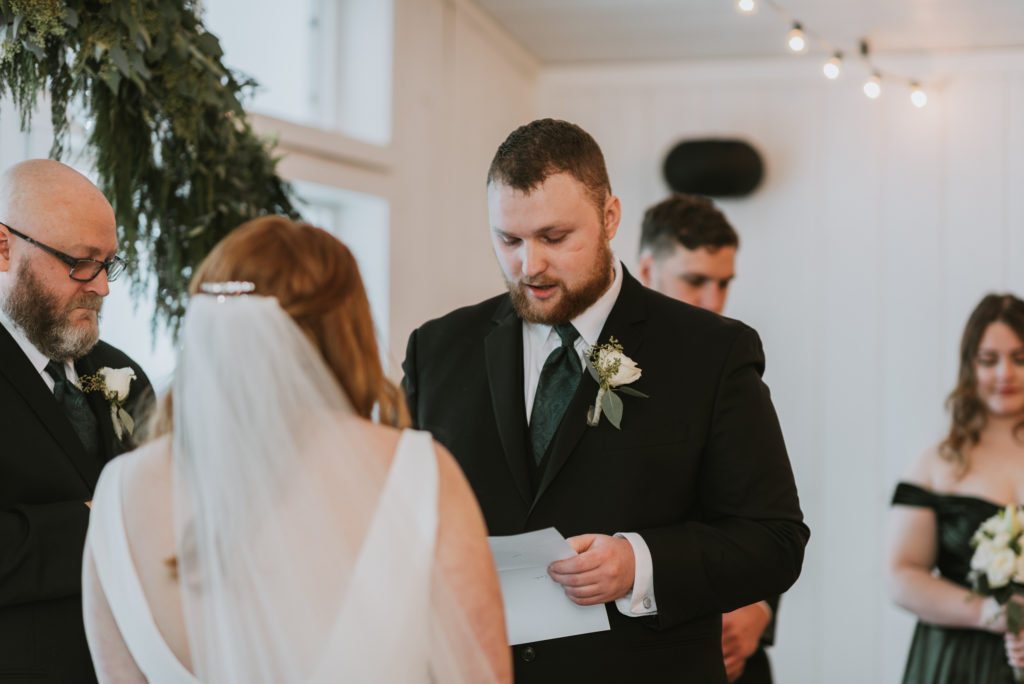 Groom reading wedding vows to wife during ceremony