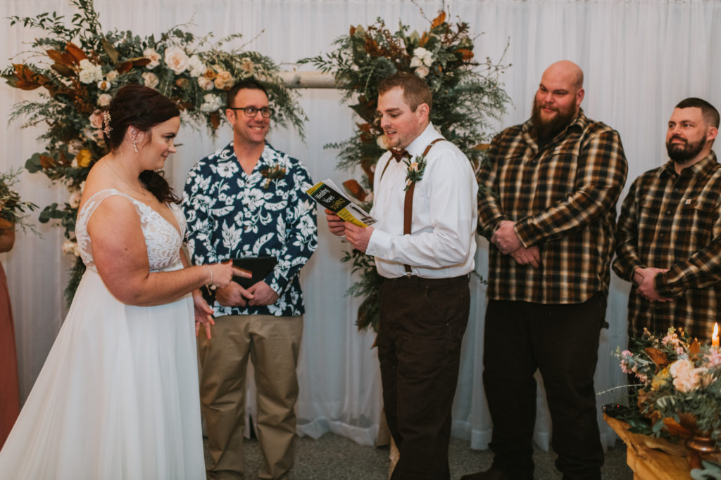 Groom reading his wedding vows during the ceremony from a wedding vows for dummies book