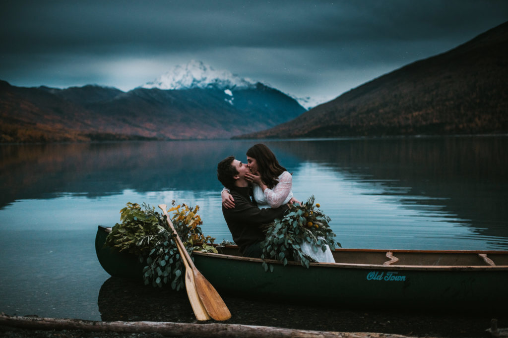 Couple kissing in a canoe on a lake with mountain views