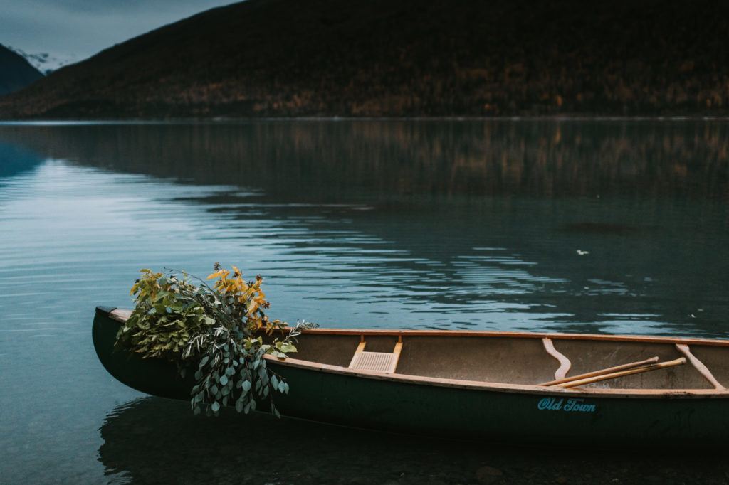 Canoe sitting in the water at Eklutna lake with birch branches