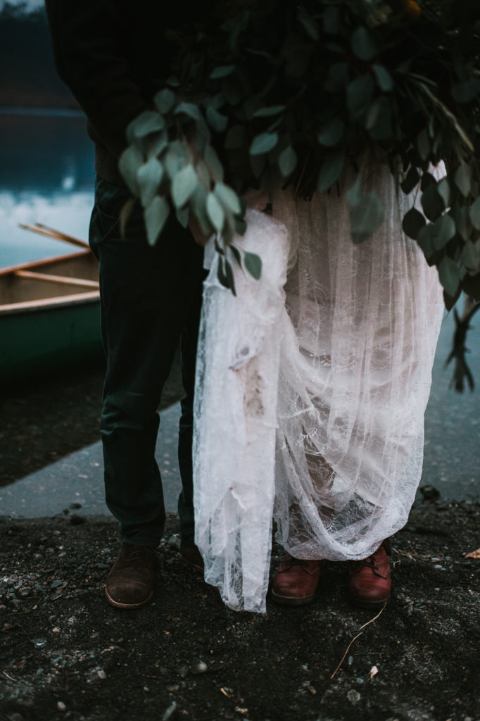 Photo of bride and grooms shoes on their elopement day with canoe and lake in the background