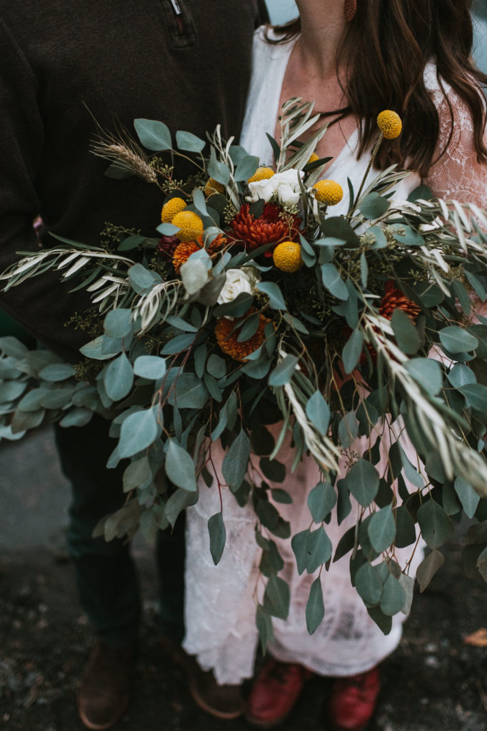 Wild and beautiful elopement bouquet with eucalyptus and orange and red flowers              