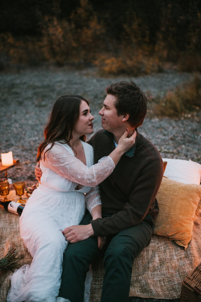 Couple snuggling during their candlelit picnic elopement on Eklutna Lake