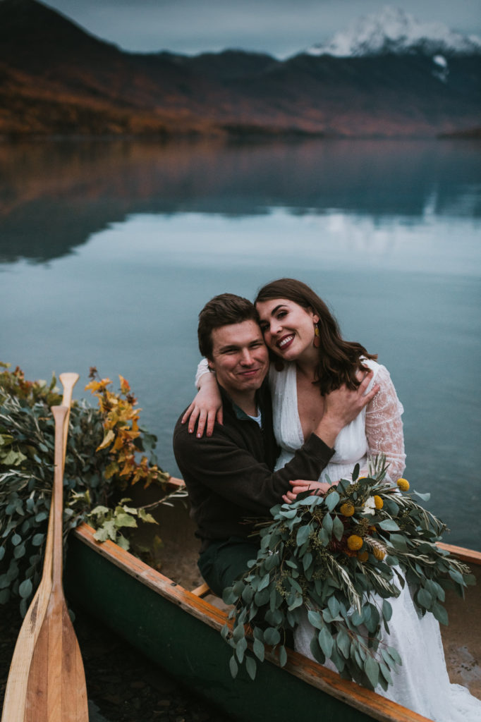 couple smiling happily on their elopement day in a canoe on a lake