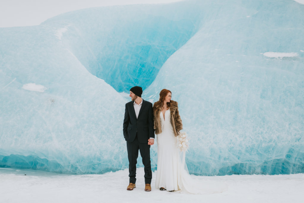 couple standing in front of an ice wall holding hands
