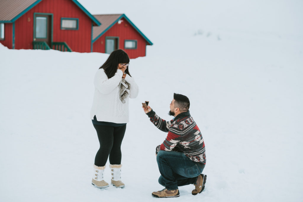 man proposing in front of red cabins up hatcher pass