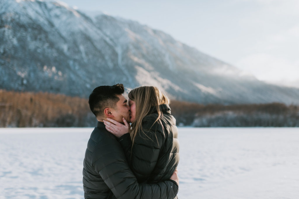 how to propose to your girlfriend in the winter couple kissing in front of mountains