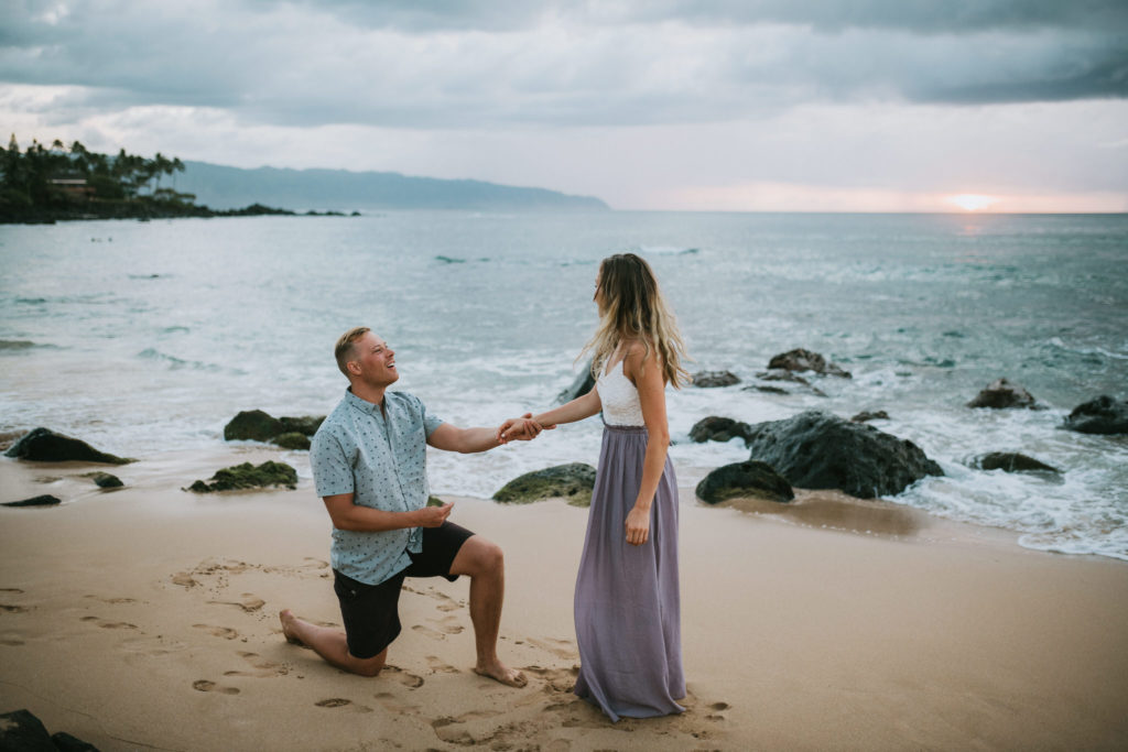man proposing to woman on beach on oahu at sunset