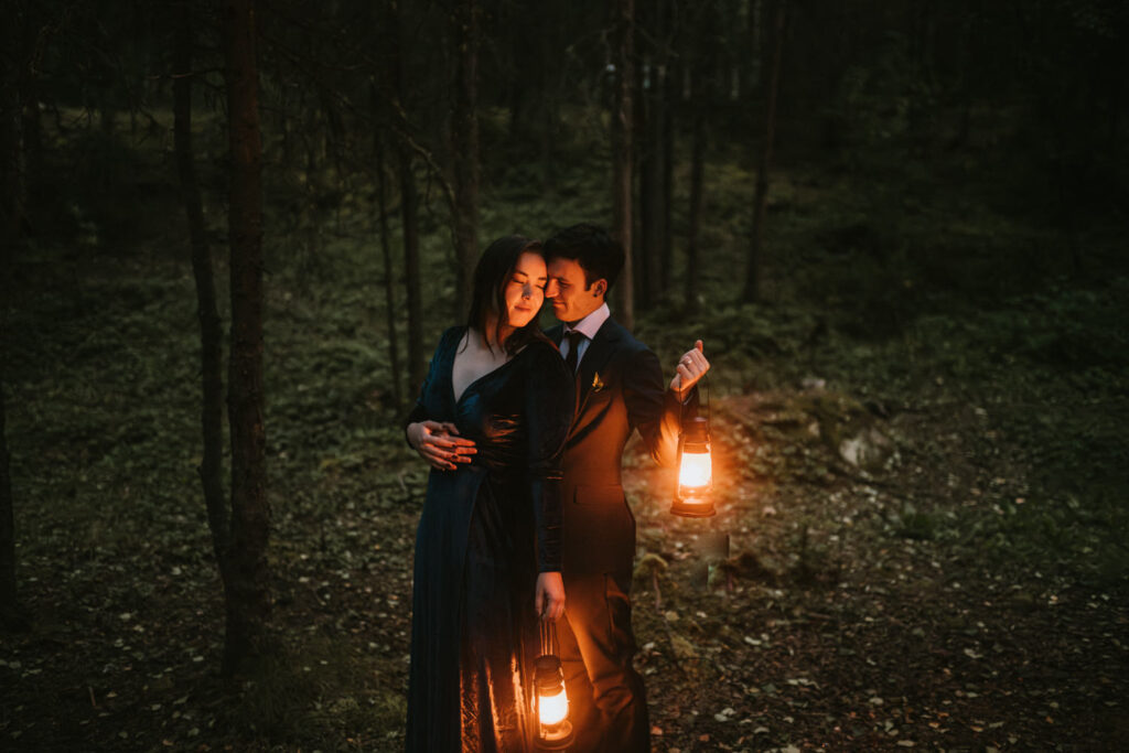 couple snuggling in the dark woods with lanterns