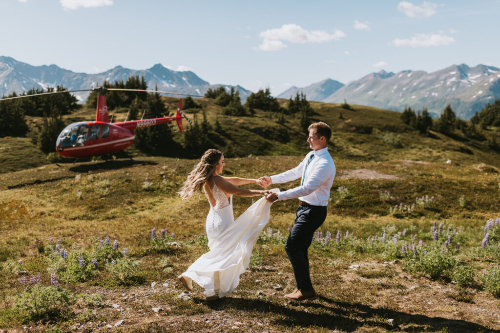 wedding couple holding hands and spinning around in a meadow