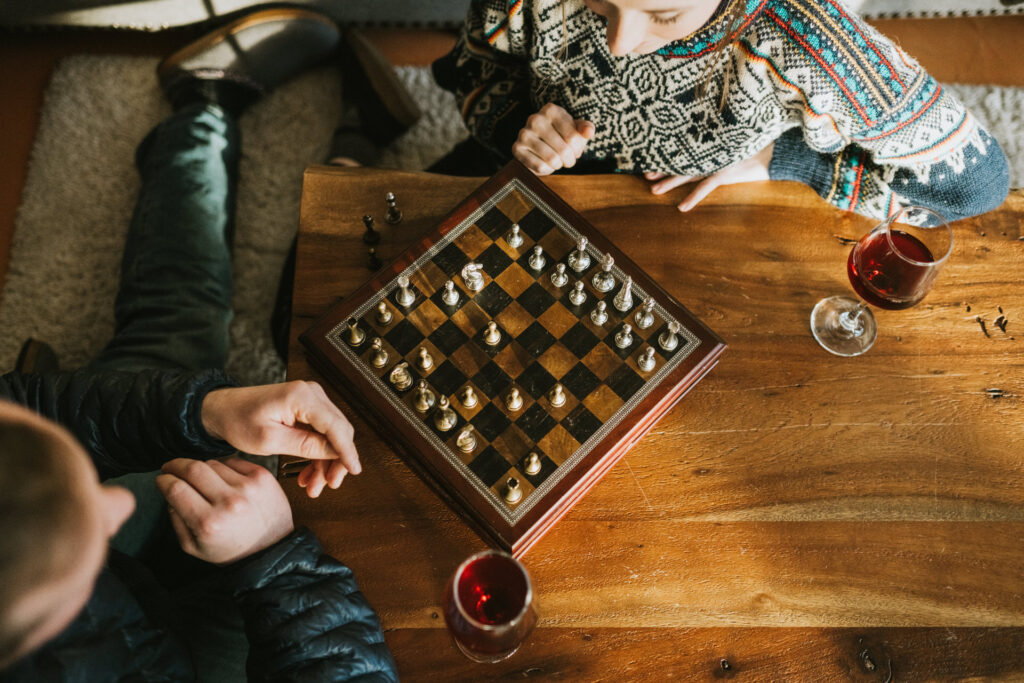 couple playing a game of chess with wine during engagement photos
