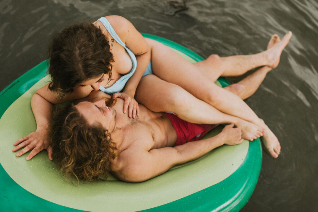 A couple relaxes and embraces on a floating tube in the water, displaying affection and comfort in each other's company, ideal for an engagement photo shoot.