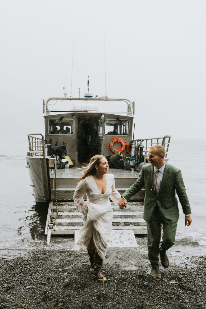 A couple in formal attire walks hand-in-hand away from a docked boat on a gray, overcast day.