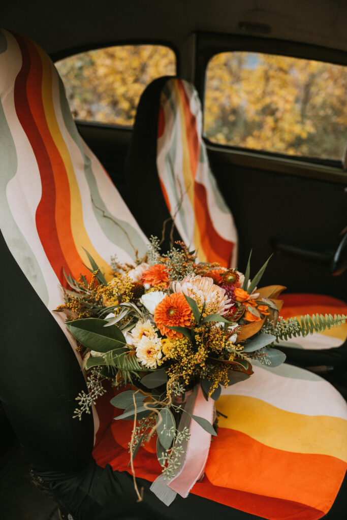 Bouquet of flowers on a car seat with multicolored striped seat covers.