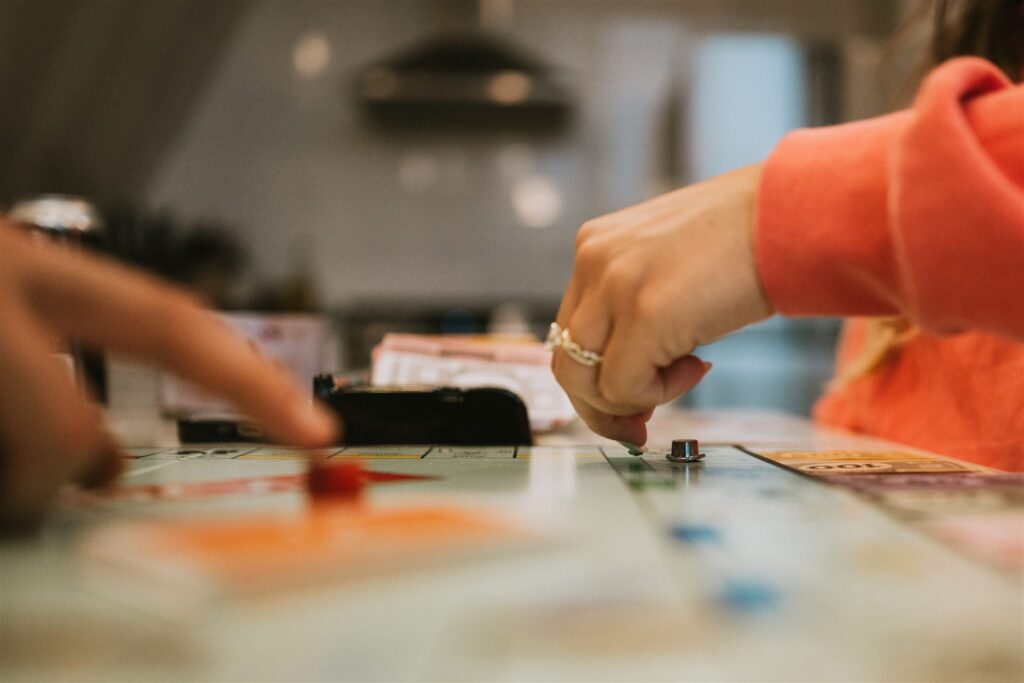 Two people playing a board game, their hands moving pieces across the board—much like a quiet lakeside elopement, the focus is on the intimate details and shared moments.
